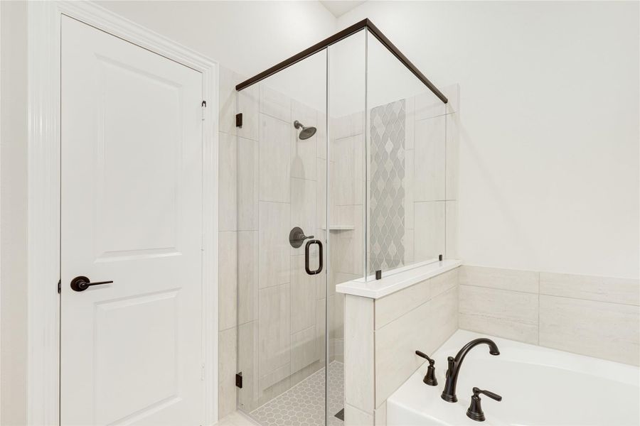 Bathroom with glass-enclosed tile shower, soaking tub, and dark bronze fixtures
