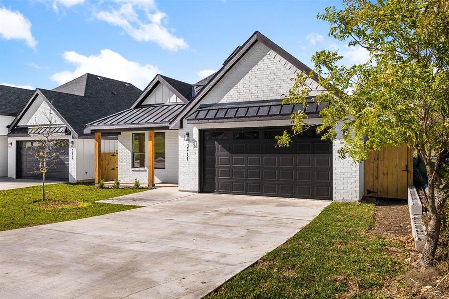 Modern inspired farmhouse featuring a front lawn and a garage