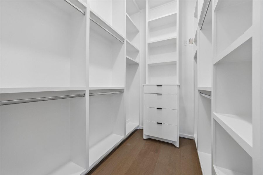 A spacious walk in closet offers custom built in storage with shelving, drawers, and abundant hanging space. A spacious walk in closet offers custom built in storage with shelving, drawers, and abundant hanging space.
