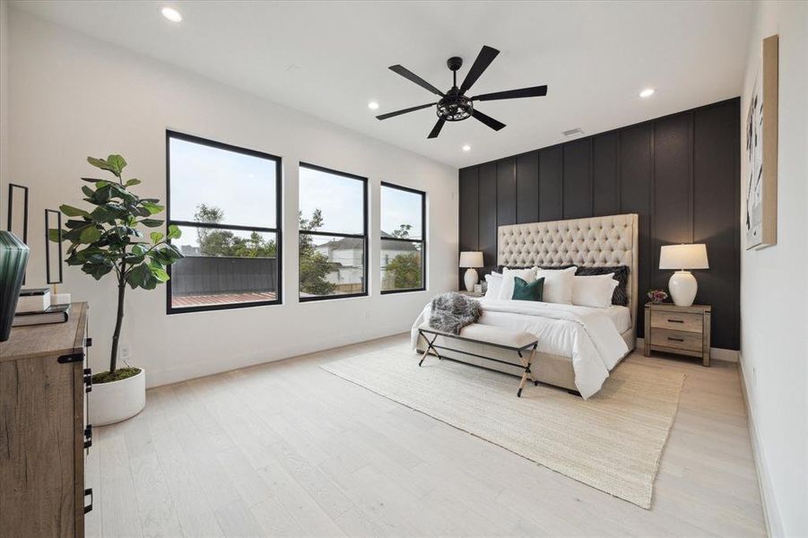 The primary bedroom has a beautifully crafted custom accent wall, white oak hardwood floors, LED lighting, ceiling fan, and wonderful high ceilings!