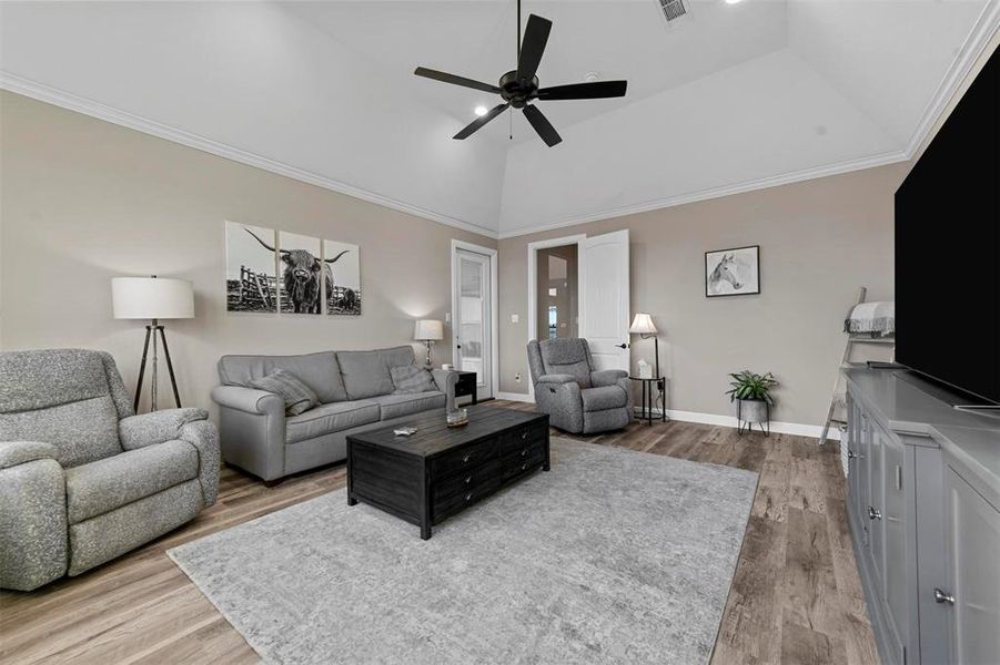 Living room featuring hardwood / wood-style floors, high vaulted ceiling, ceiling fan, and ornamental molding