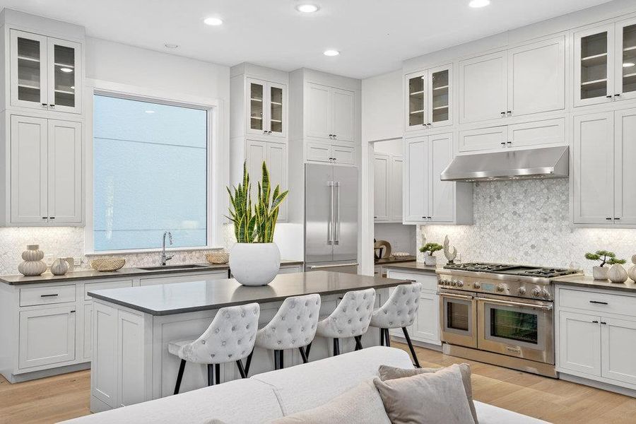 Kitchen featuring decorative backsplash, high quality appliances, white cabinets, glass insert cabinets, and recessed lighting