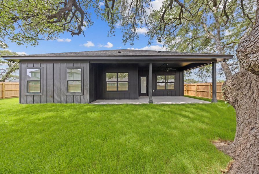 A well-maintained lawn extends from a covered patio on this modern home's rear exterior. A well-maintained lawn extends from a covered patio on this modern home's rear exterior.