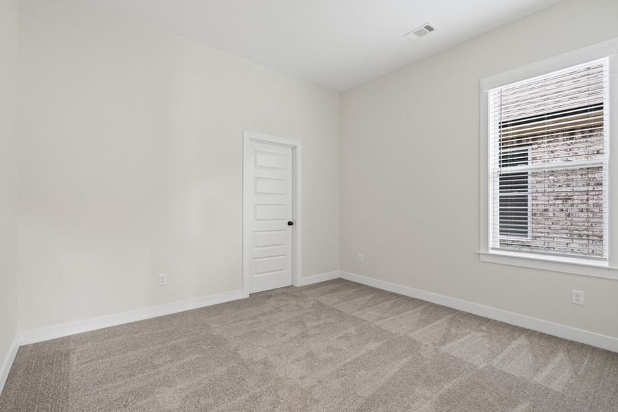 Neutral wall paint with textured carpeting, a single window featuring blinds, a multi-panel door, and white baseboards Neutral wall paint with textured carpeting, a single window featuring blinds, a multi-panel door, and white baseboards