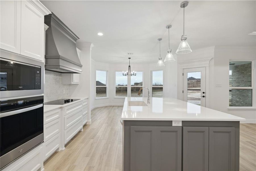 Kitchen featuring stainless steel appliances, a center island with sink, sink, and custom exhaust hood