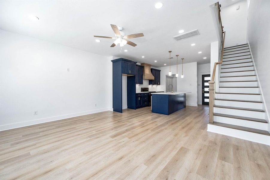 Wide view capturing the open living area, staircase detail, and seamless connection to the kitchen.
