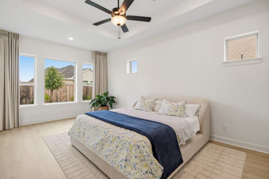 Sunlit bedroom featuring oversized windows, a stylish ceiling fan, and tasteful finishes that create a calm and inviting retreat.