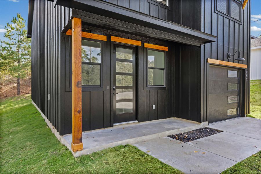 Property entrance with board and batten siding and a yard