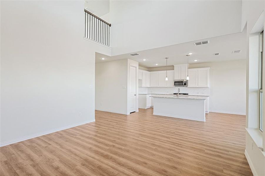 Unfurnished living room featuring light wood-style flooring, recessed lighting, and a high ceiling