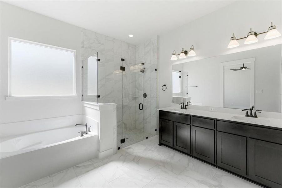 Full bath featuring double vanity, a marble finish shower, plenty of natural light, a garden tub, and recessed lighting
