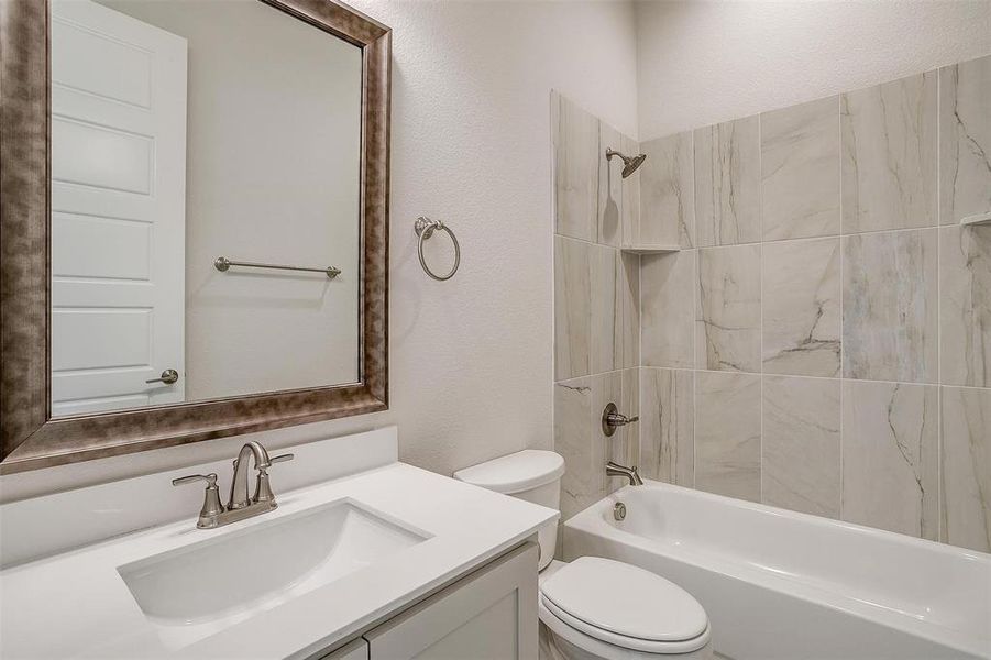 Full bathroom with vanity, tiled shower / bath combo, and toilet