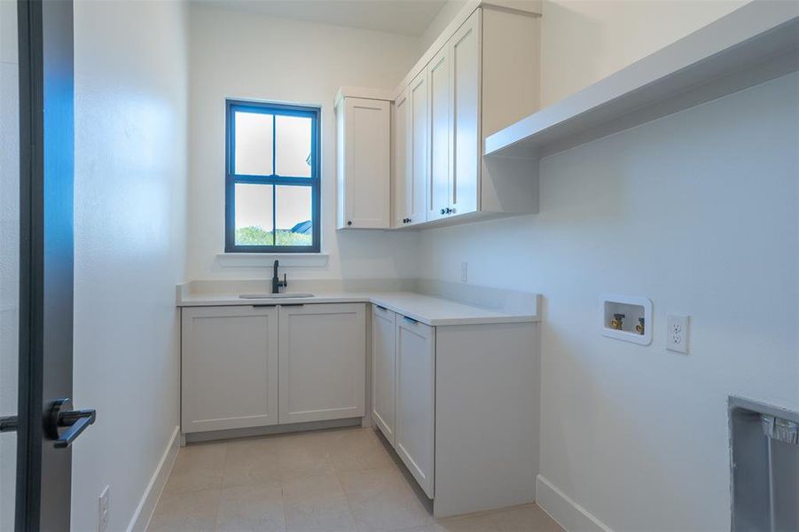 Clothes washing area featuring cabinets, hookup for a washing machine, and sink