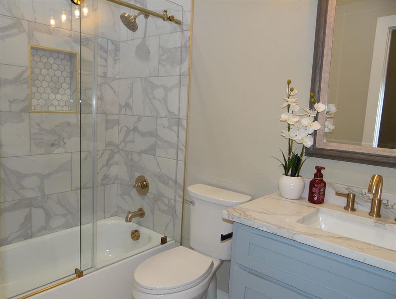 Full bathroom with vanity, shower / bath combination with glass door, and toilet