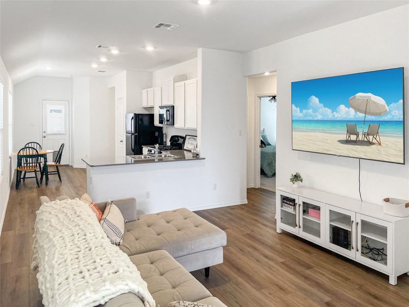 Open layout with vinyl plank flooring in living areas and carpet in bedrooms