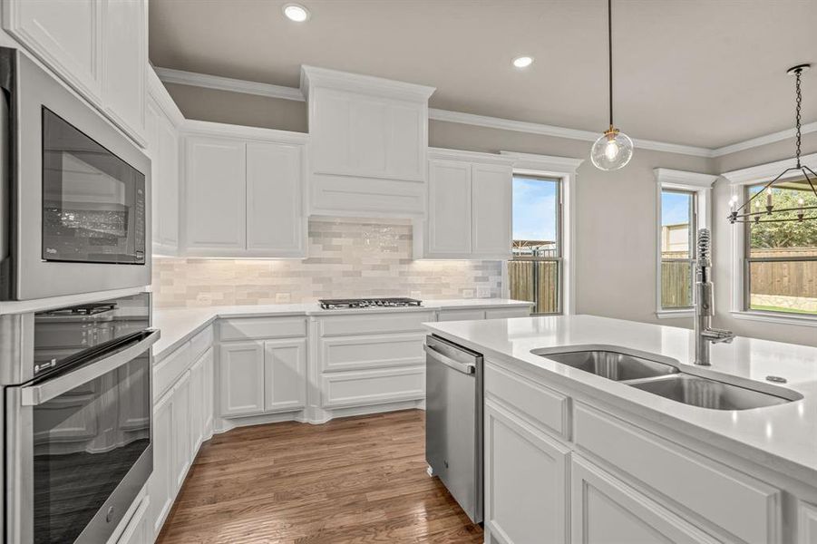Kitchen featuring white cabinetry, ornamental molding, stainless steel appliances, backsplash, and recessed lighting Kitchen featuring white cabinetry, ornamental molding, stainless steel appliances, backsplash, and recessed lighting