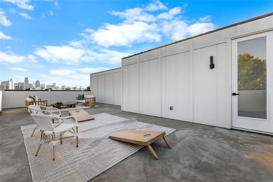 Rooftop deck featuring a city skyline, concrete flooring, and modern white paneling Rooftop deck featuring a city skyline, concrete flooring, and modern white paneling