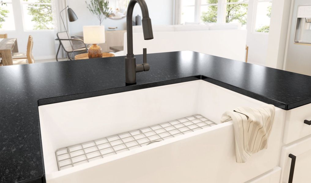 White apron front sink within the kitchen featuring matte black faucets