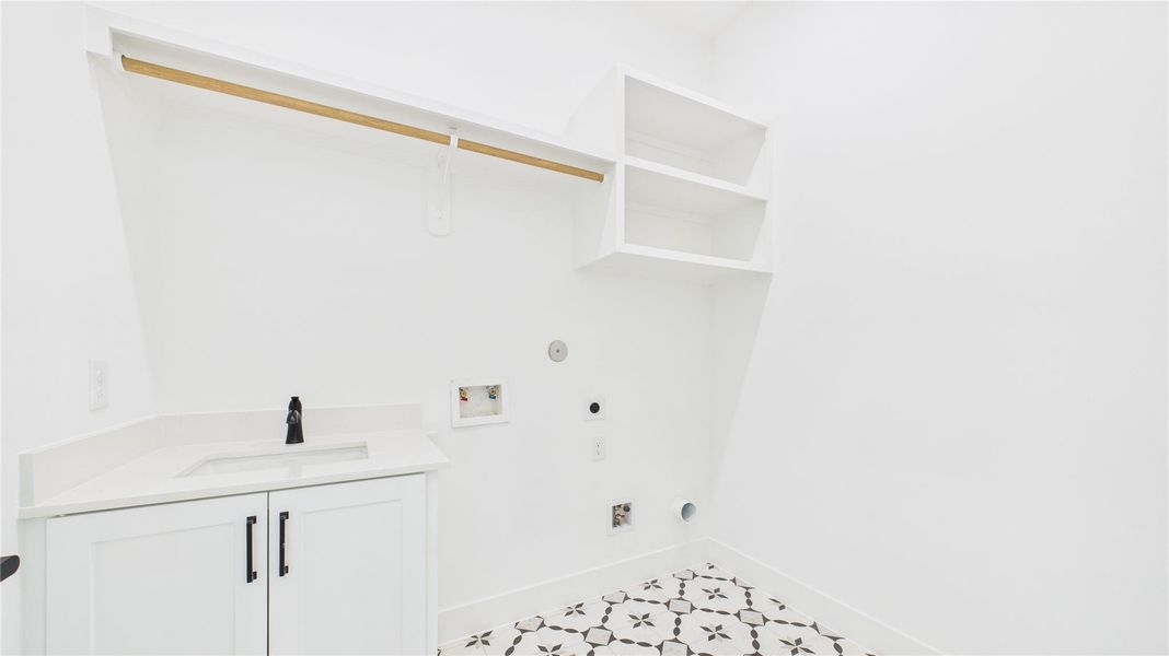 The second floor utility room features cabinetry, open shelving, and a patterned tile floor. It includes a space for a washer and dryer and ample storage.
