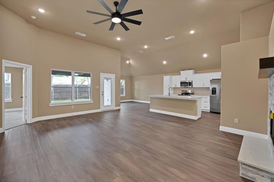 Unfurnished living room featuring visible vents, a ceiling fan, baseboards, and dark wood-style flooring Unfurnished living room featuring visible vents, a ceiling fan, baseboards, and dark wood-style flooring