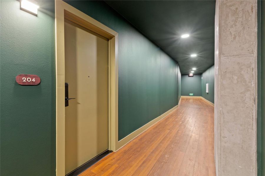 Richly hued walls and warm wood flooring frame a modern residential hallway corridor.