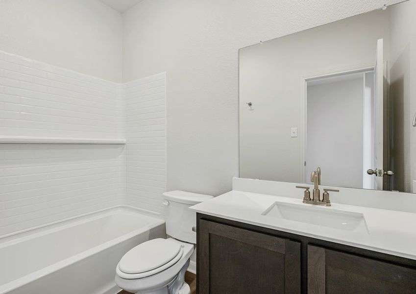 The secondary bathroom has a sprawling vanity and a shower-tub combo.