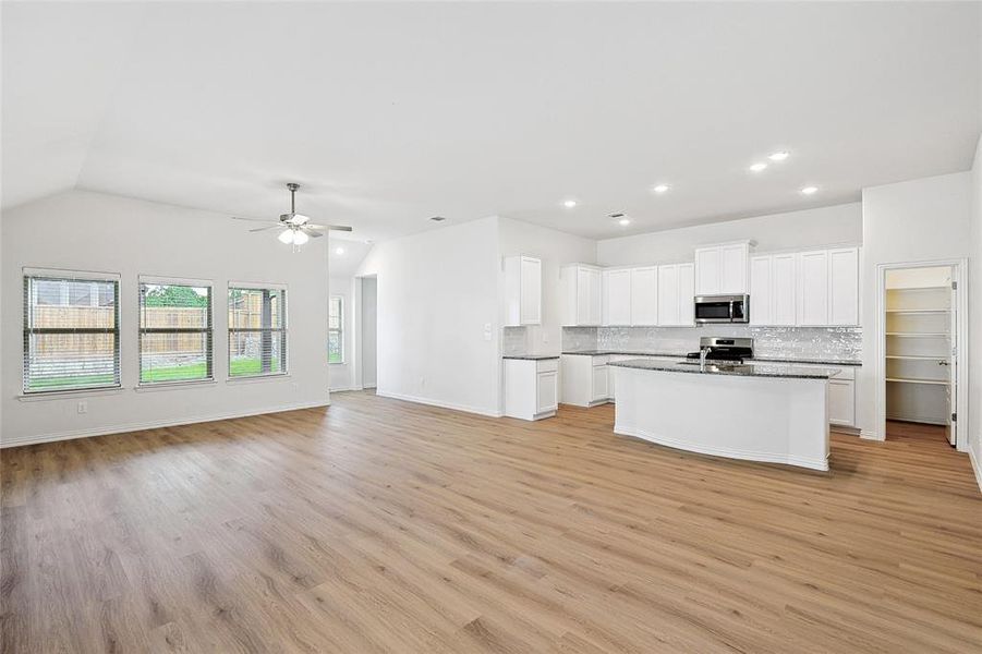 Kitchen with stainless steel appliances, ceiling fan, light hardwood / wood-style flooring, and tasteful backsplash