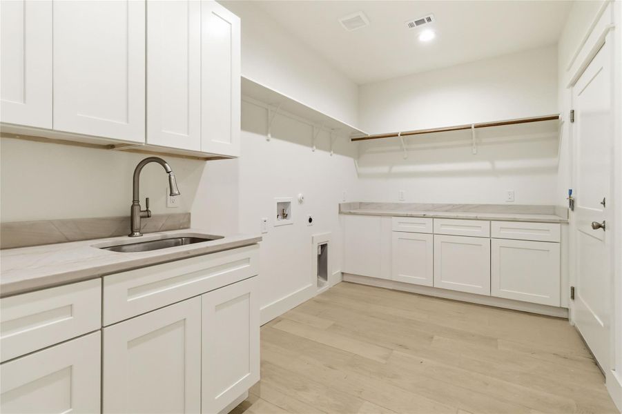 Expansive laundry room with cabinets, sink and extended shelving