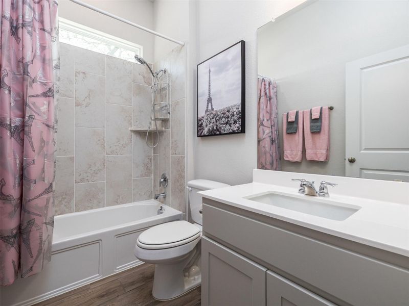 Bathroom with vanity, shower / bath combination with curtain, and dark wood finished floors