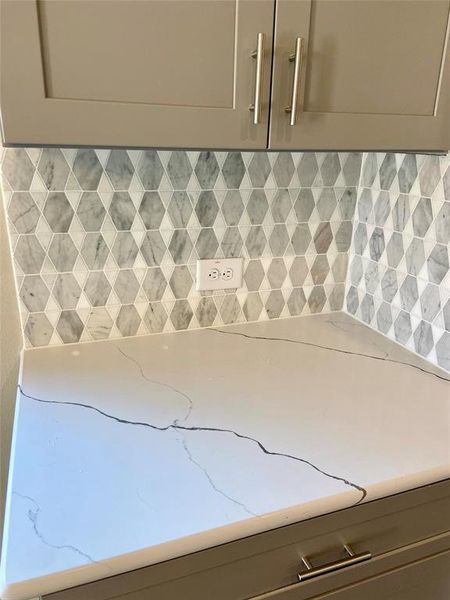 Close up of Shaker Grey cabinets with hardware & soft closing doors & drawers. Mosaic tile backsplash is stylish, and elegant Monet Quartz countertops.