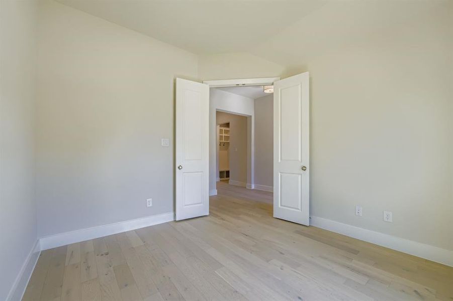 Spare room with light wood-style floors and vaulted ceiling