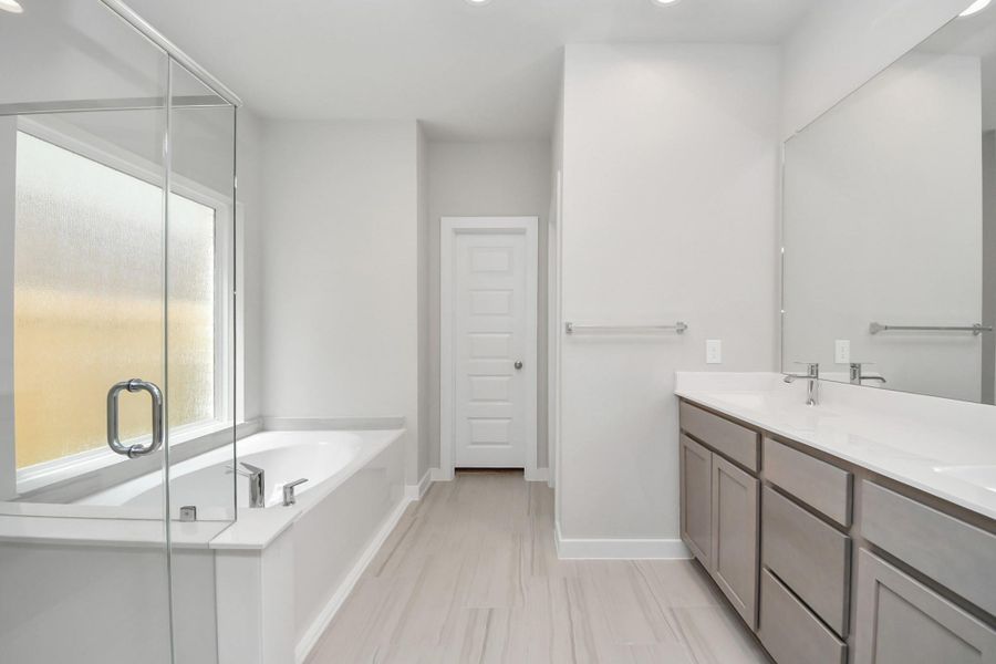 Escape to a spa-like oasis in this primary bathroom. Enjoy a walk-in shower with tile surround, a separate garden tub with custom detailing, and an elegant vanity featuring light countertops, modern hardware, and beautiful recessed lights. Experience luxury and relaxation in every detail. Escape to a spa-like oasis in this primary bathroom. Enjoy a walk-in shower with tile surround, a separate garden tub with custom detailing, and an elegant vanity featuring light countertops, modern hardware, and beautiful recessed lights. Experience luxury and relaxation in every detail.