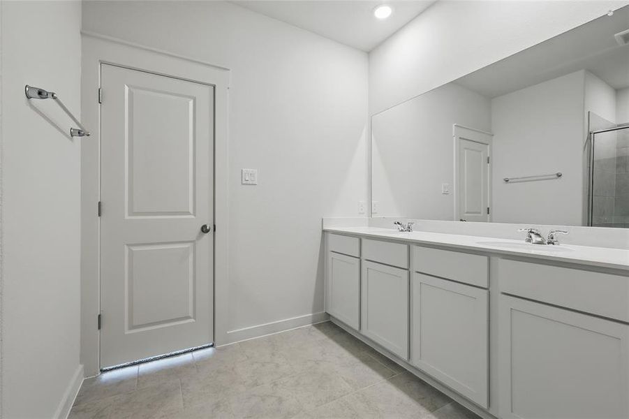 Bathroom featuring baseboards, double vanity, tiled shower, and recessed lighting Bathroom featuring baseboards, double vanity, tiled shower, and recessed lighting