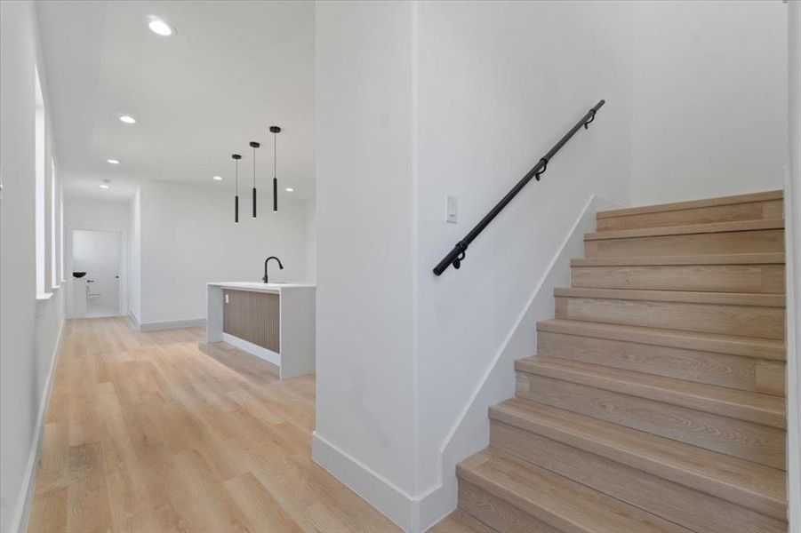 Stairs featuring baseboards, wood finished floors, and recessed lighting