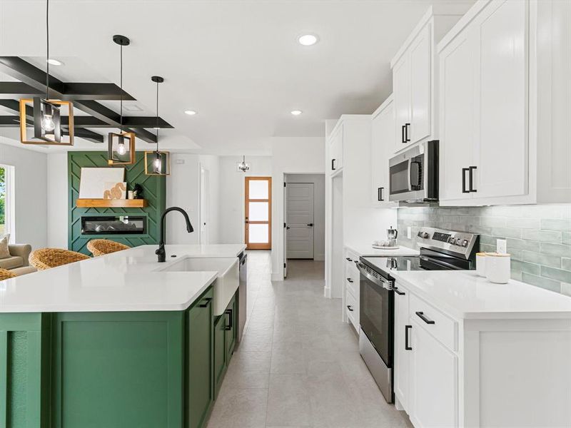 Kitchen featuring appliances with stainless steel finishes, white cabinets, green cabinetry, a kitchen island with sink, and light stone countertops