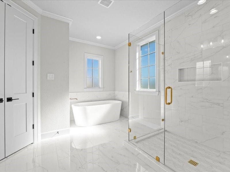 Full bath with a soaking tub, a marble finish shower, a wainscoted wall, marble finish floors, and crown molding Full bath with a soaking tub, a marble finish shower, a wainscoted wall, marble finish floors, and crown molding
