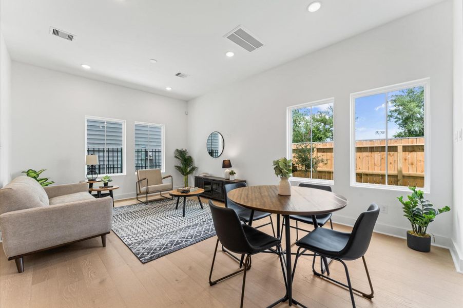 Designed for modern living, this open-concept space seamlessly unites the kitchen, dining, and living areas into one harmonious hub. The kitchen anchors the layout with a large center island, sleek cabinetry, and pendant lighting that adds a touch of sophistication. Just steps away, the dining area offers ample room for gatherings, while the spacious living room invites relaxation with abundant natural light and flexible seating.