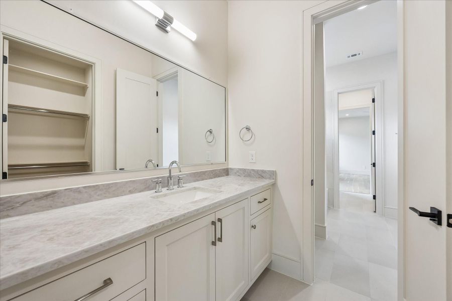 Quartz countertops, generous vanity storage, and a spacious walk in closet create a functional ensuite designed for everyday comfort. Clean lines and timeless finishes offer a bright, polished look that complements the adjoining bedroom.