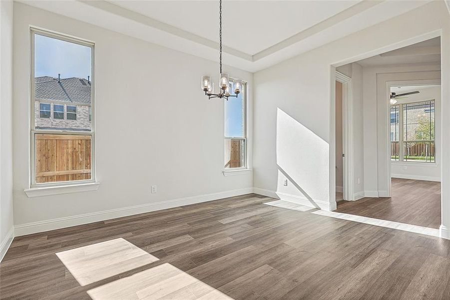 Unfurnished dining area featuring dark hardwood / wood-style floors and ceiling fan with notable chandelier