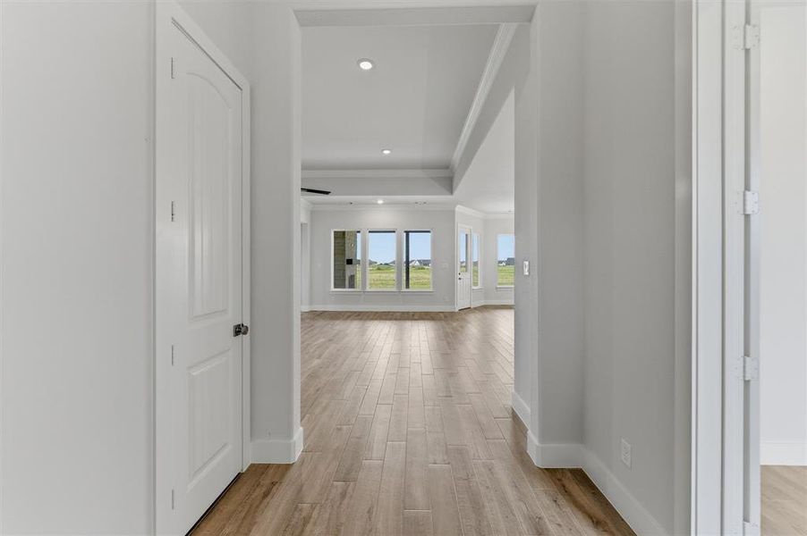 Hallway featuring wood-finish flooring, white trim, recessed lighting, and a white interior door