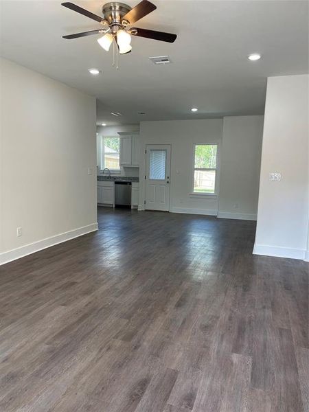 Unfurnished living room featuring ceiling fan, dark hardwood / wood-style floors, and sink