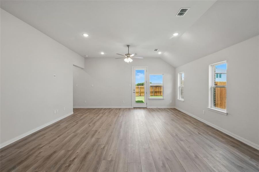 Unfurnished living room with light wood-style floors, ceiling fan, lofted ceiling, baseboards, and recessed lighting Unfurnished living room with light wood-style floors, ceiling fan, lofted ceiling, baseboards, and recessed lighting