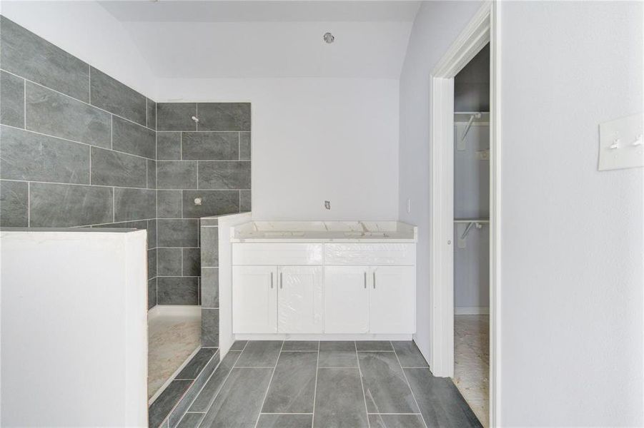 This modern bathroom features sleek tile work and a spacious shower area, offering a spa-like experience right at home. The clean lines and contemporary finishes make it a serene space to start and end your day. **This image is from another Saratoga Home - Athena floorplan.**