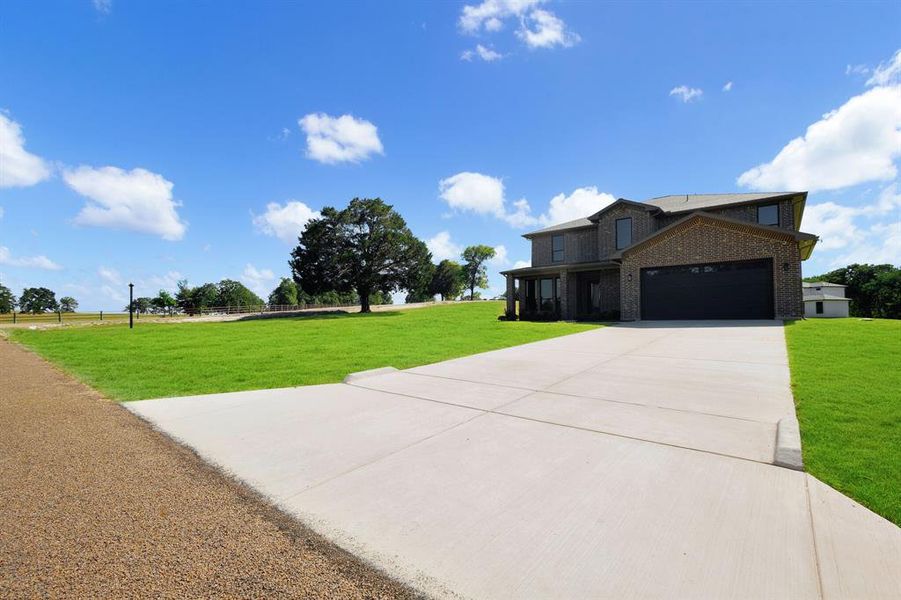 Two-story brick exterior with a prominent concrete driveway and attached garage Two-story brick exterior with a prominent concrete driveway and attached garage