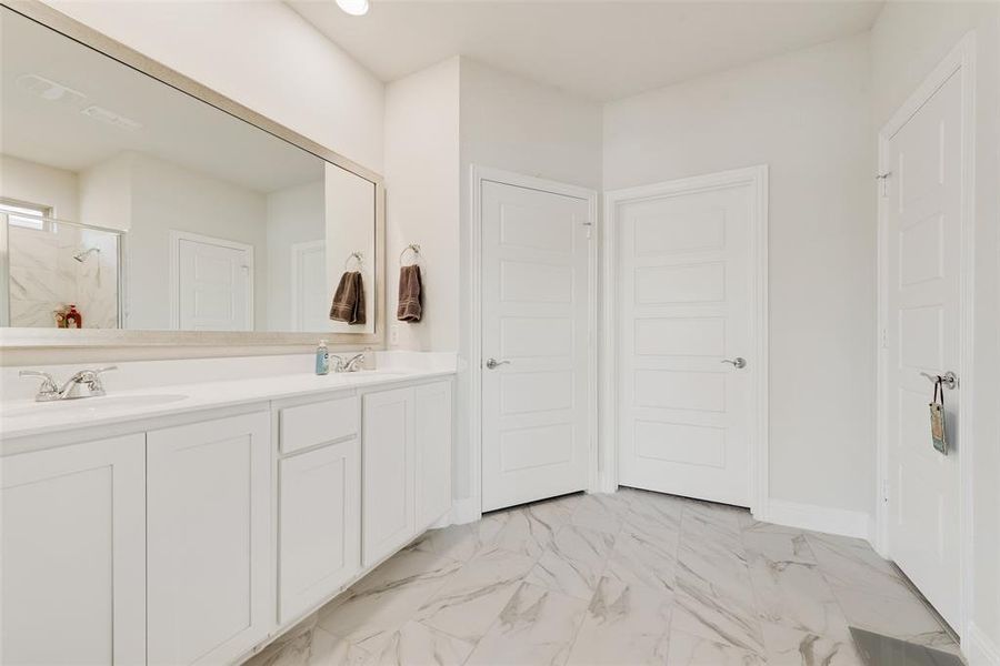 Primary Bathroom featuring double vanity, a marble finish shower, and light marble finish floors Primary Bathroom featuring double vanity, a marble finish shower, and light marble finish floors