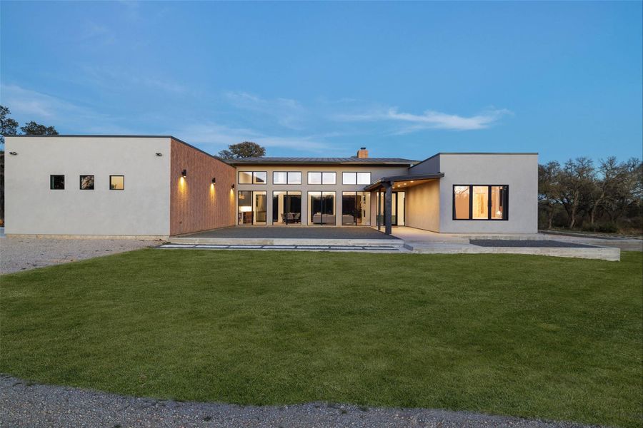 Back of property featuring a patio, a lawn, a chimney, and stucco siding