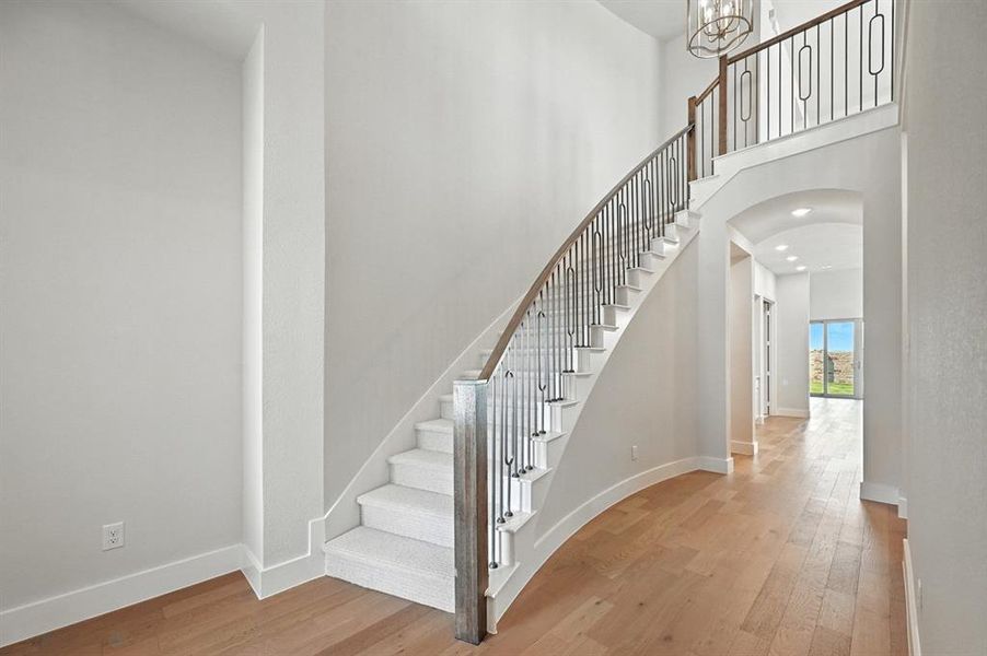 Stairs with arched walkways, wood finished floors, and a high ceiling Stairs with arched walkways, wood finished floors, and a high ceiling