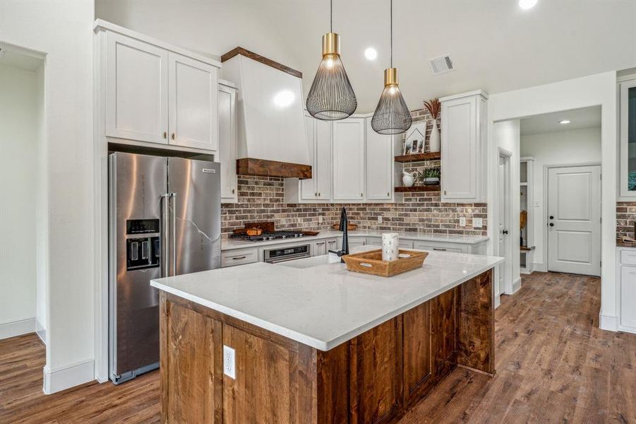 Kitchen with decorative backsplash, a kitchen island with sink, light hardwood / wood-style flooring, and high quality fridge