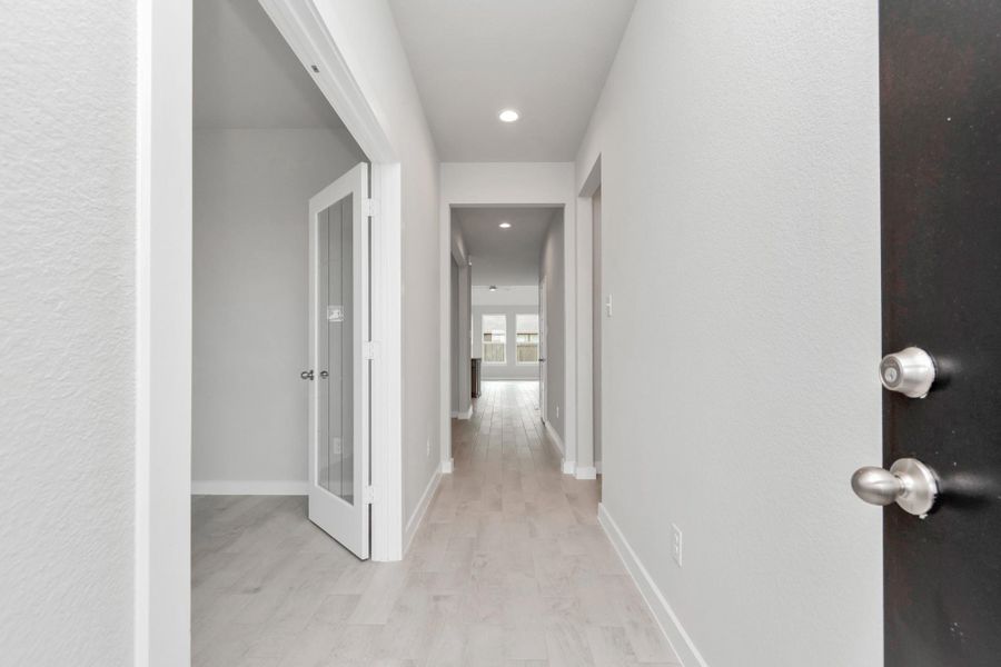 The grand entrance beckons with high ceilings, adorned with elegant wood-look tile flooring and oversized baseboards, and recessed lighting. Follow path of natural light from expansive windows ahead. Sample photo of completed home with similar floor plan. As-built interior colors and selections may vary. The grand entrance beckons with high ceilings, adorned with elegant wood-look tile flooring and oversized baseboards, and recessed lighting. Follow path of natural light from expansive windows ahead. Sample photo of completed home with similar floor plan. As-built interior colors and selections may vary.