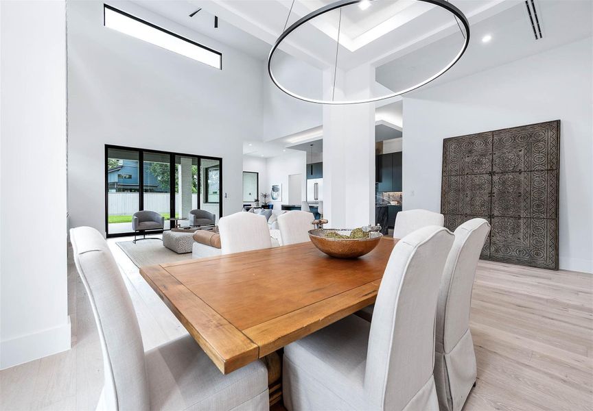 Dining room featuring an elegant recessed ceiling and a stylish chandelier with three adjustable color settings, creating the perfect ambiance for any occasion.