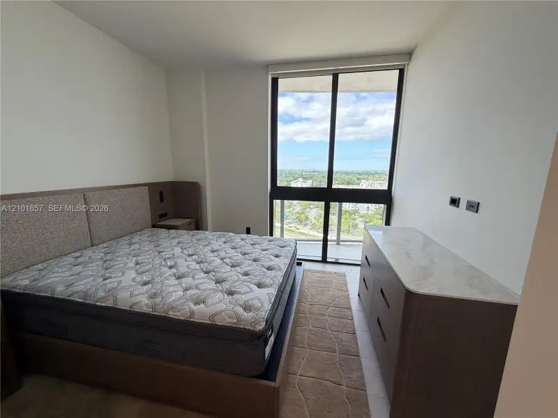 Floor-to-ceiling windows, tile flooring, and exterior balcony access